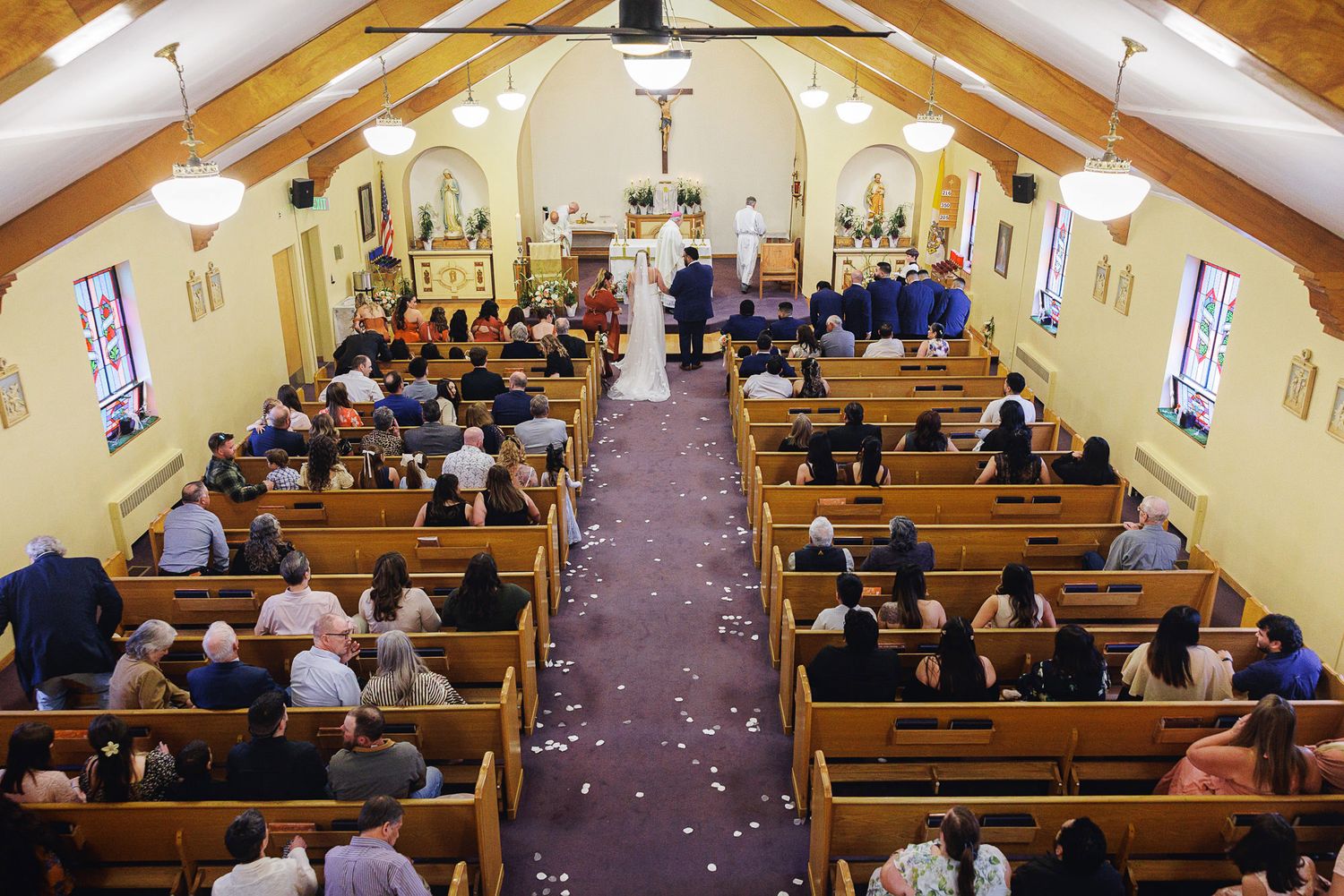 Elegant church wedding ceremony with guests seated in wooden pews as couple stands at the altar.