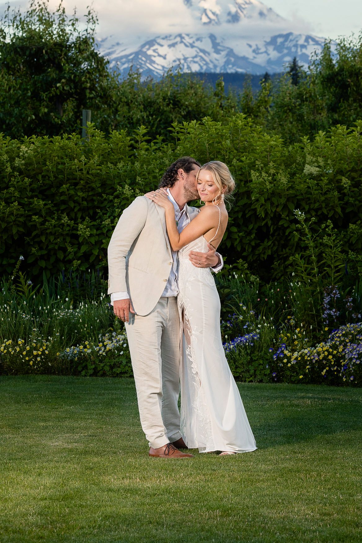 A couple shares an intimate moment with snow-capped mountains in the background.