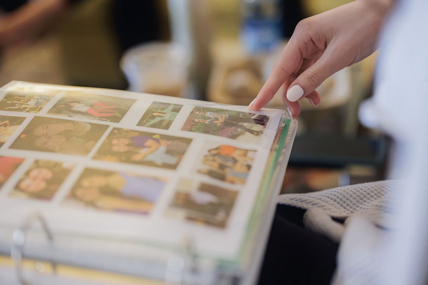A hand points to photos in an open stamp collection album, showing vintage postage stamps arranged on the pages.