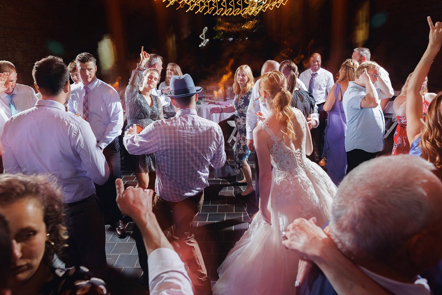 Bride and groom dancing joyfully with guests at a lively wedding reception celebration.