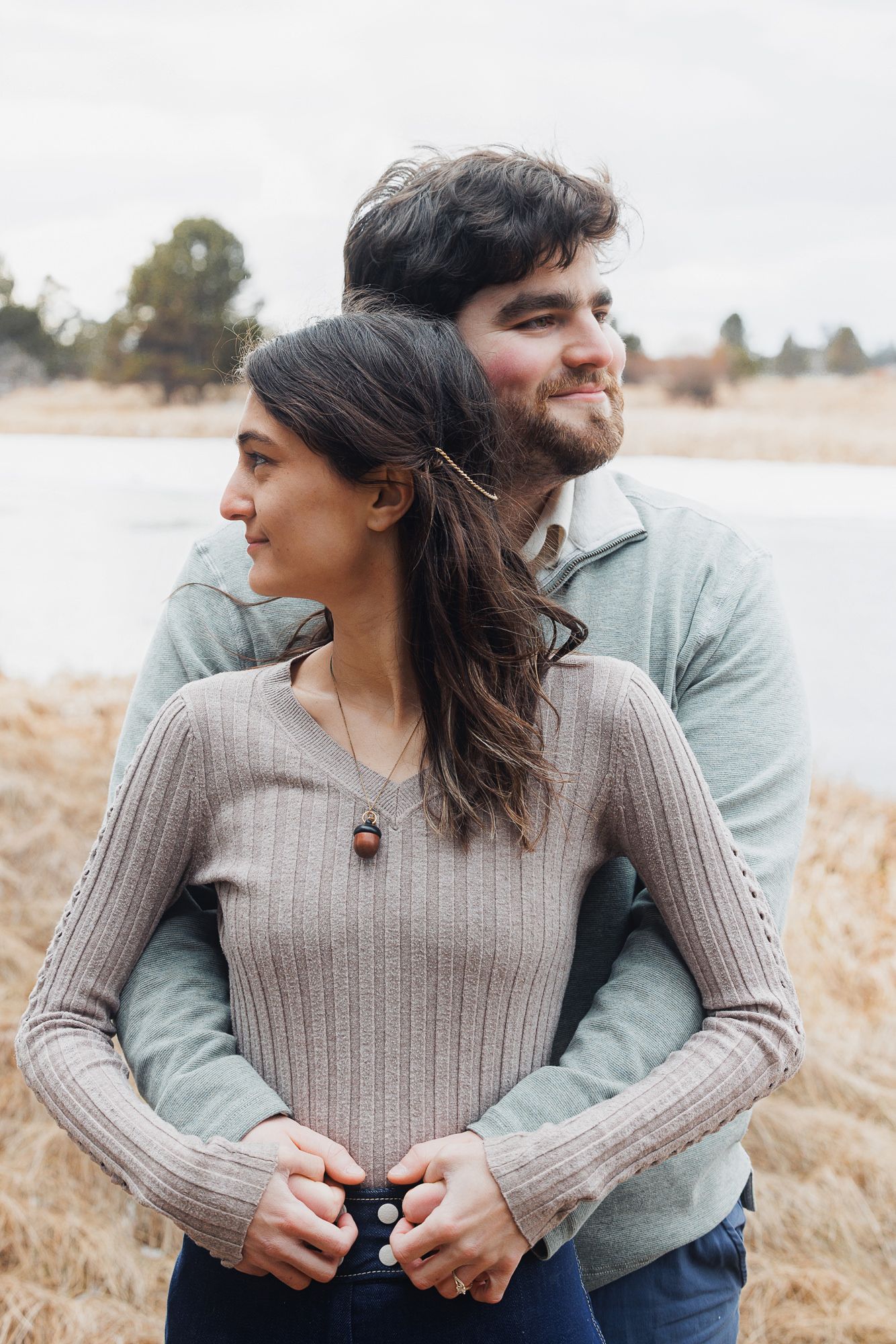 A couple embraces in a golden field during autumn while wearing cozy sweaters and sharing intimate moments.