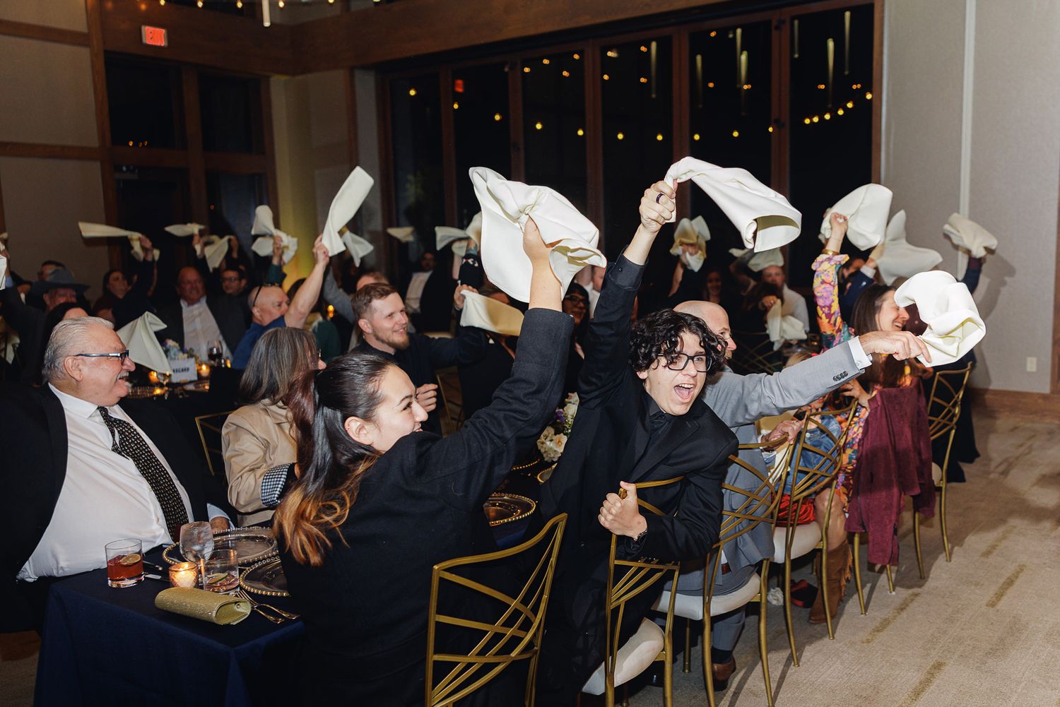 A panoramic view of a dimly lit event space with people seated at tables during a social gathering.