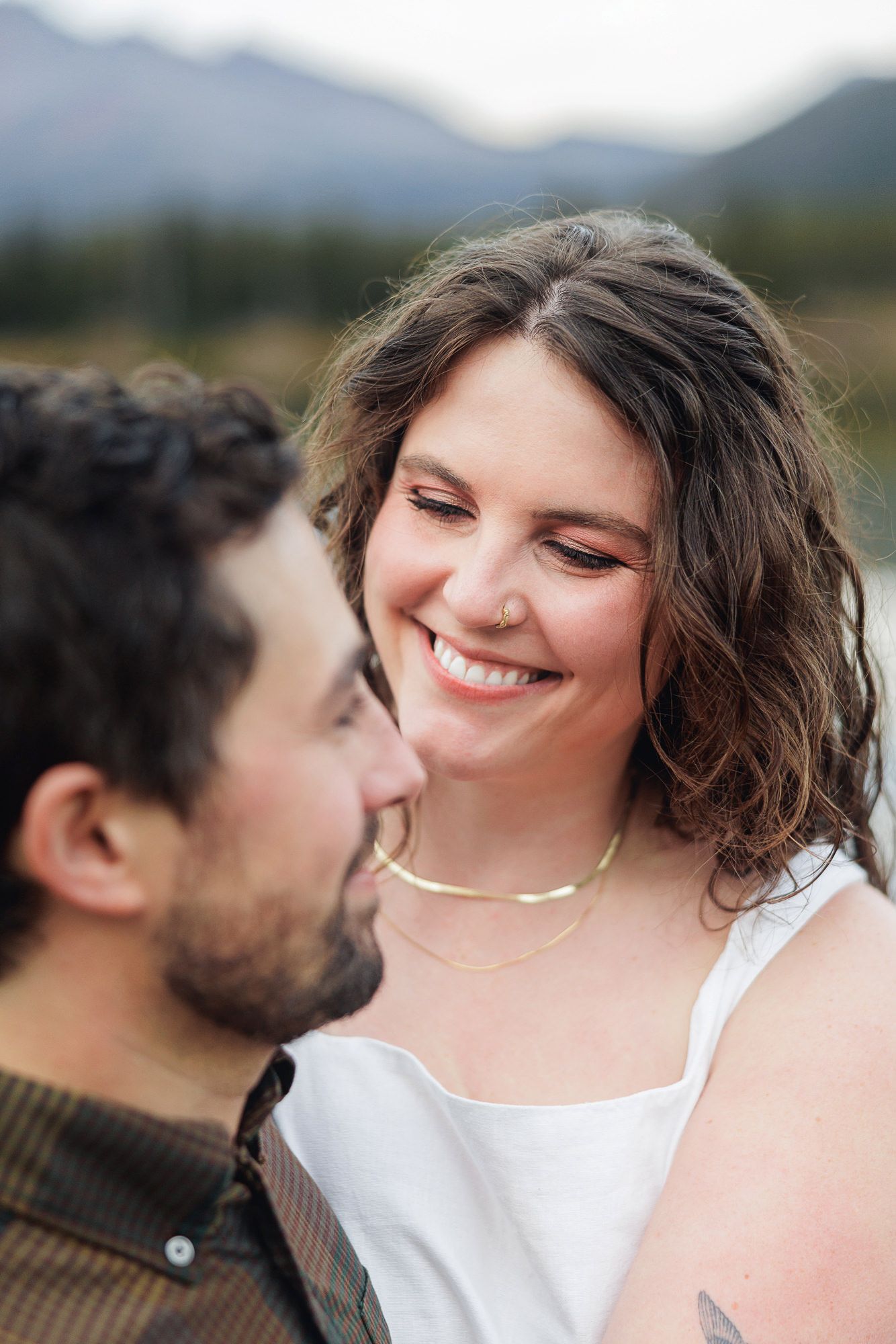 A loving couple shares an intimate moment together against a mountain backdrop.