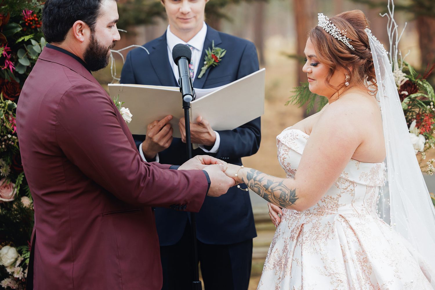 Wedding party members share heartfelt moments during a fall outdoor ceremony with burgundy accents.