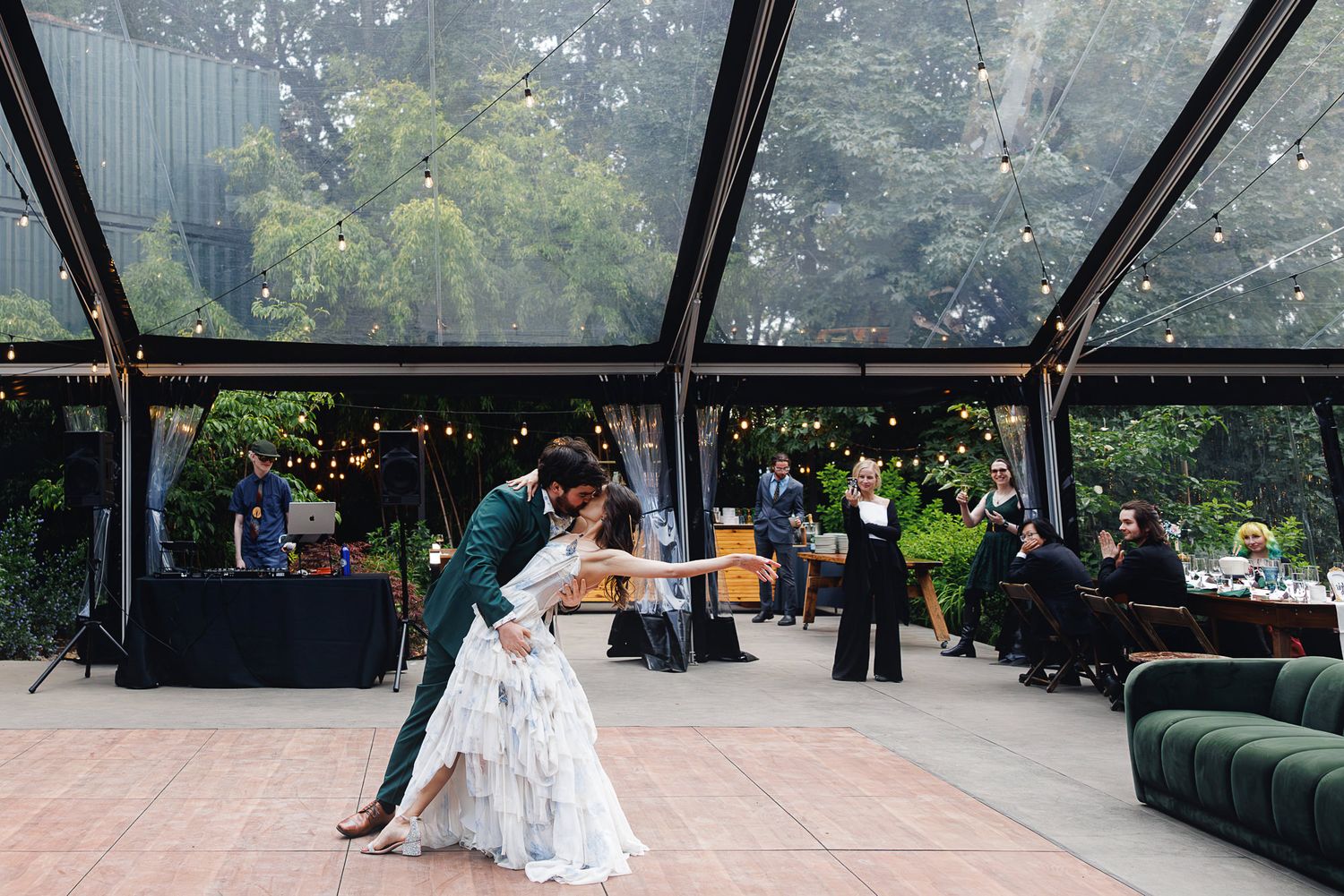 Couple shares romantic first dance dip under string lights in elegant outdoor tent wedding reception.