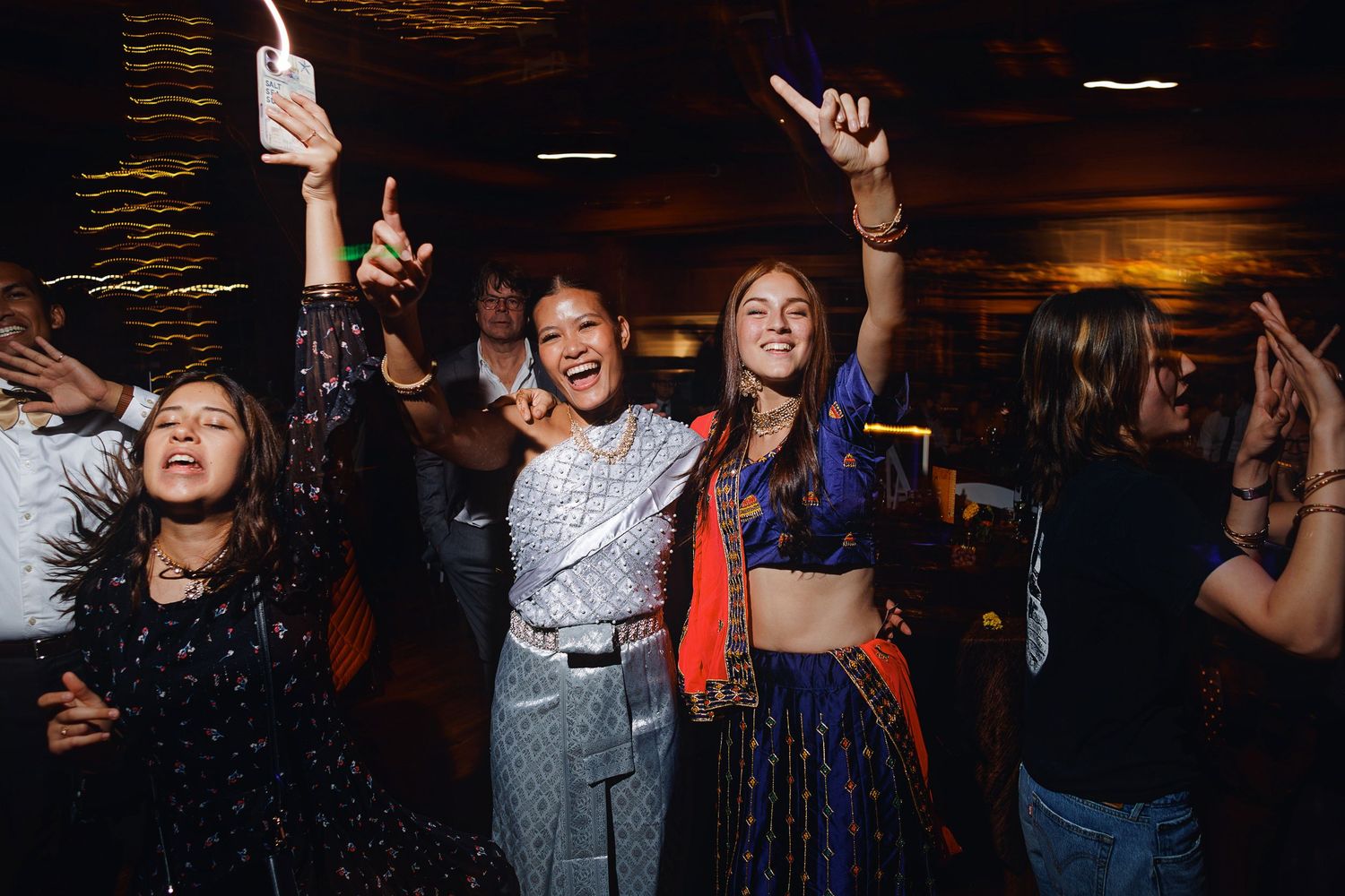 Women in colorful traditional Indian attire dancing joyfully at a festive celebration party.