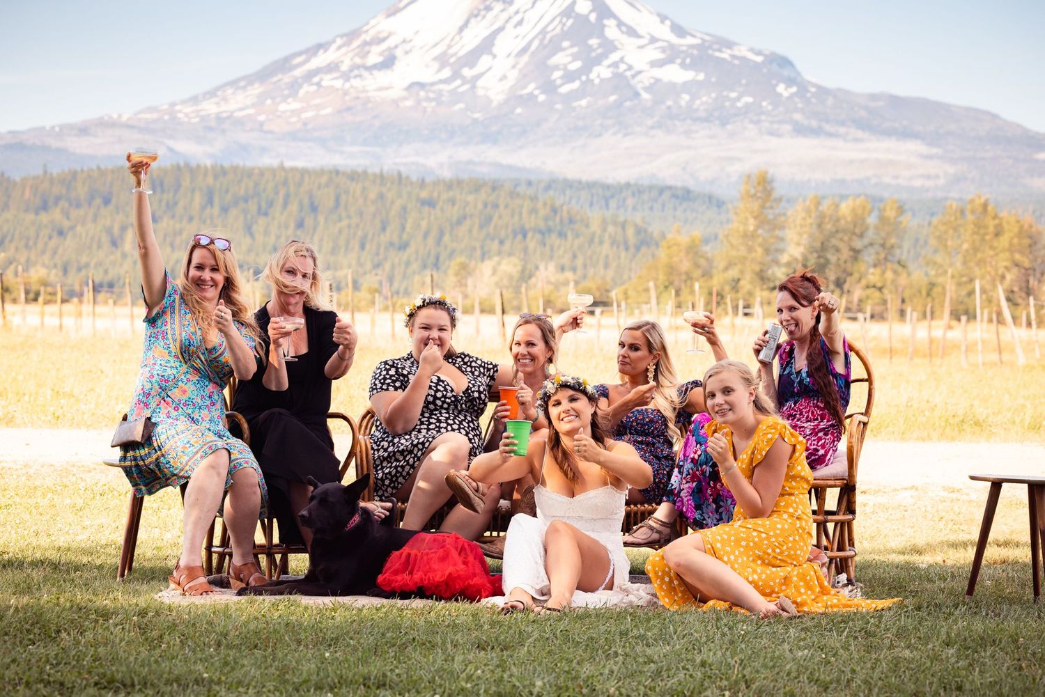 A joyful group celebration on a grass field with Mount Adams towering in the background on a sunny day.