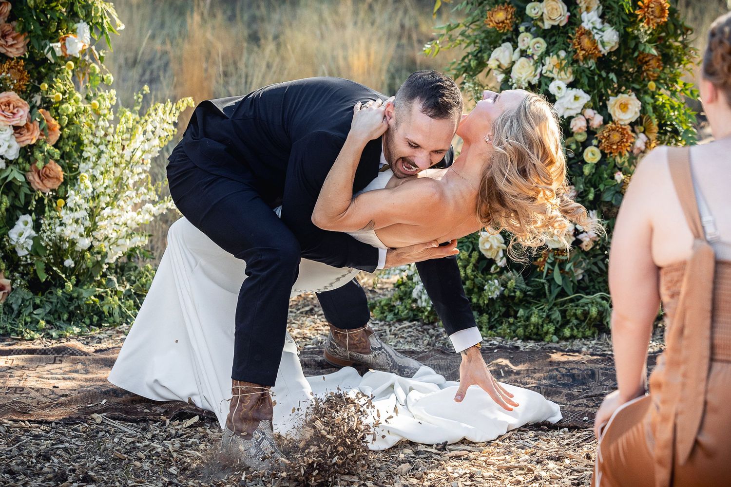 A joyful wedding moment captured under a floral arch in natural lighting.