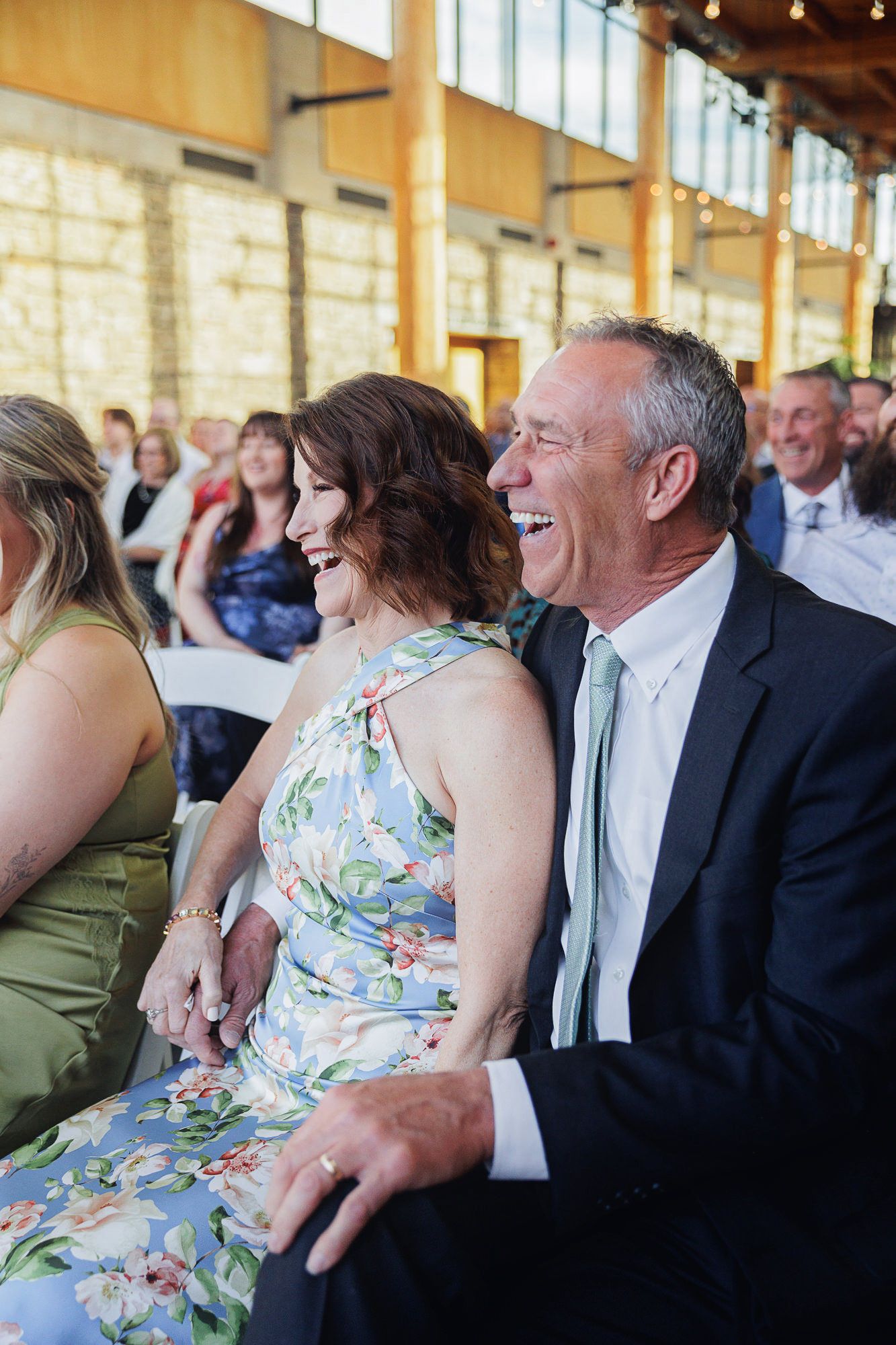 A couple laughing joyfully together at a wedding reception in an elegant venue.