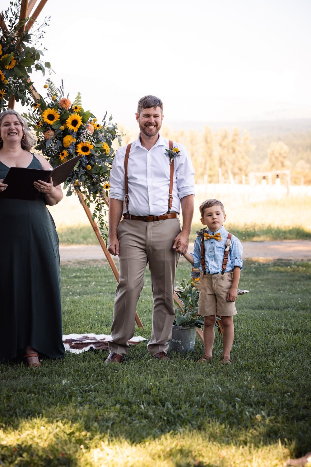 A rustic outdoor wedding ceremony setup with sunflowers and autumn decor against a scenic mountain backdrop at sunset.
