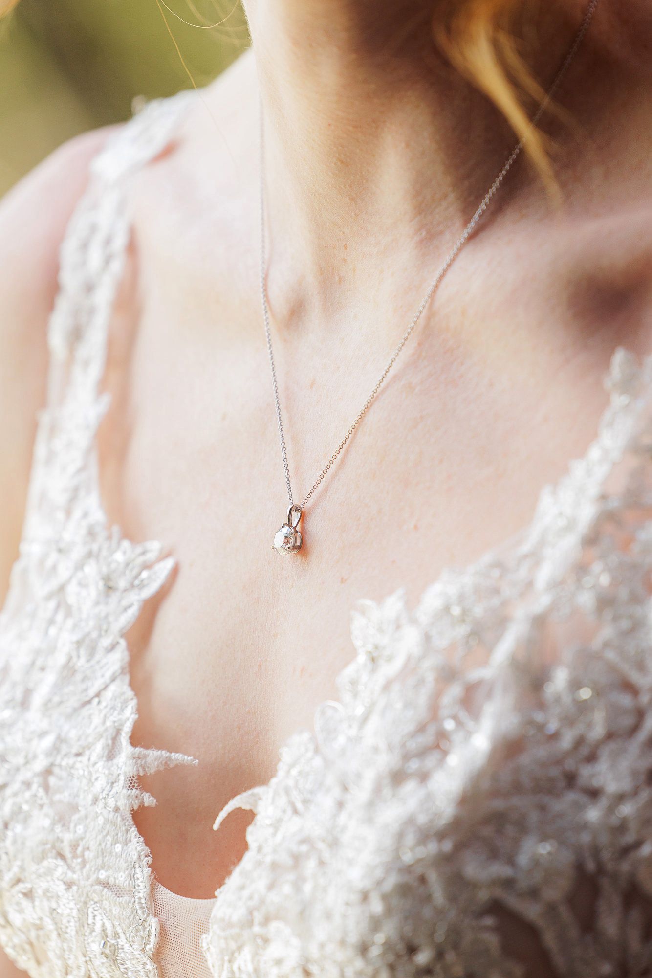 Bride wearing lace wedding dress with elegant silver heart locket necklace on delicate chain.