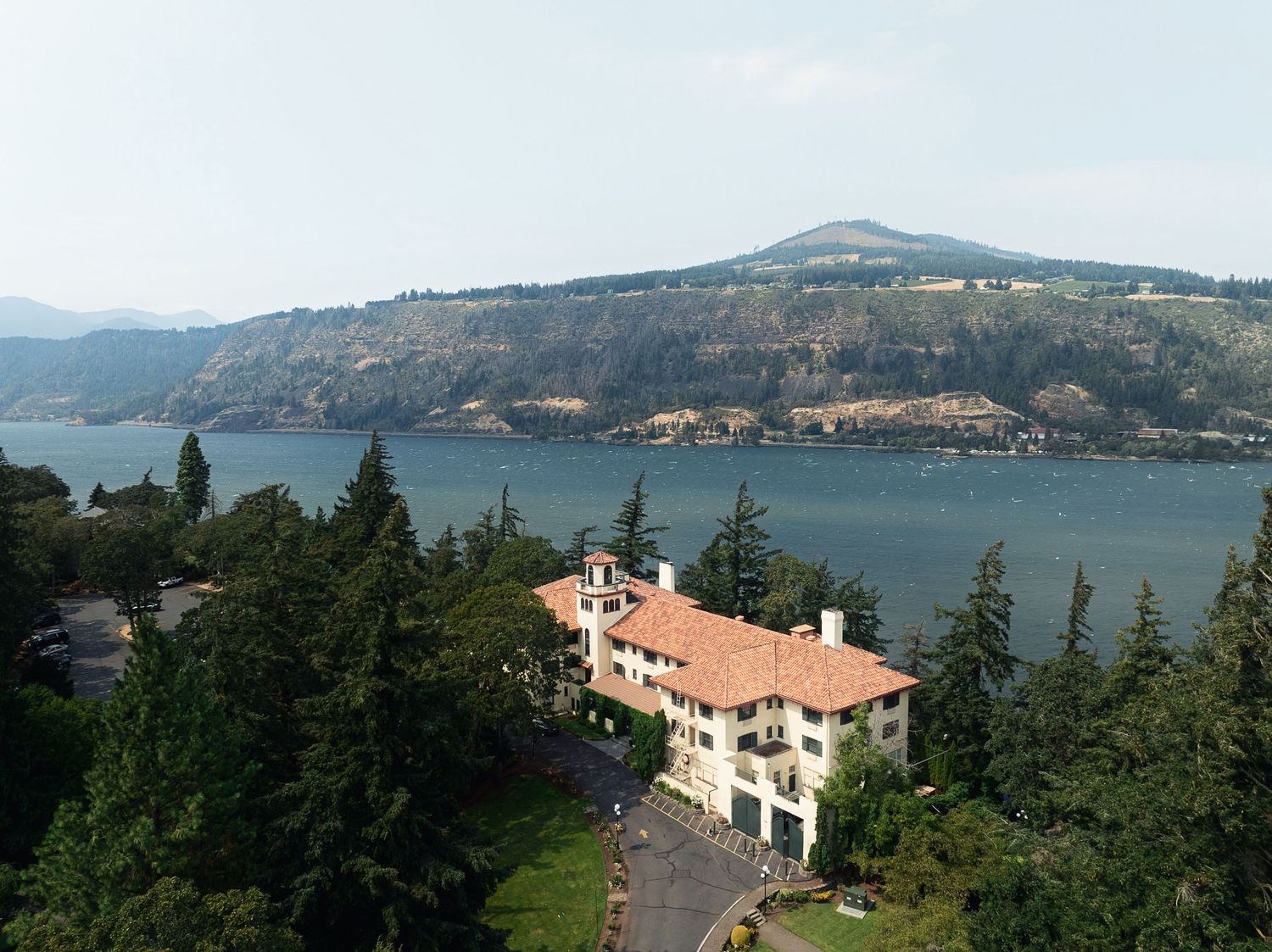 Aerial view of a Mediterranean-style villa nestled among evergreen trees overlooking the Columbia River Gorge.