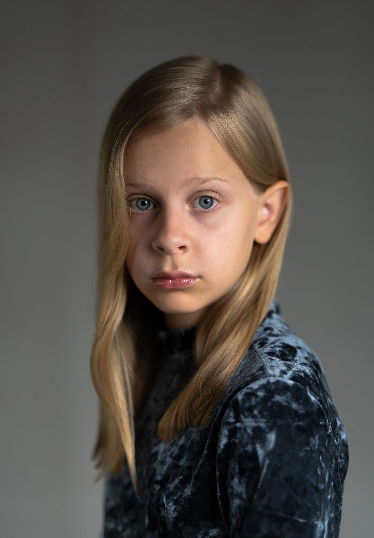Someone in a blue velvet dress poses against a neutral background in multiple artistic portrait views.