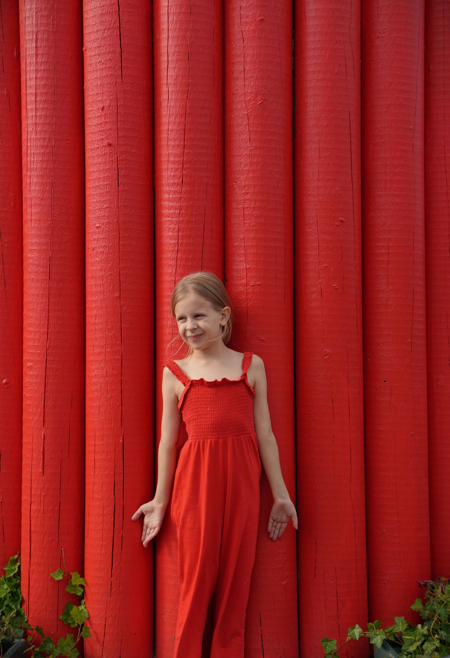 A portrait against vibrant red vertical panels creating a striking visual contrast.