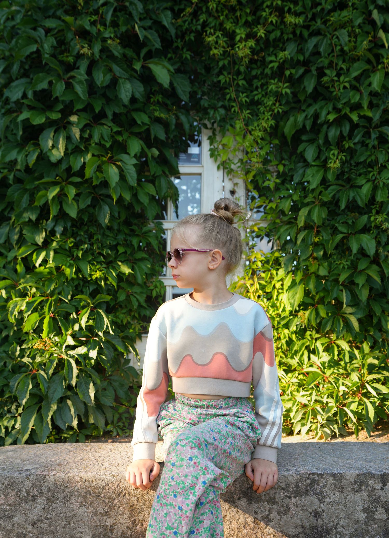 A fashion portrait against lush green foliage in natural sunlight.