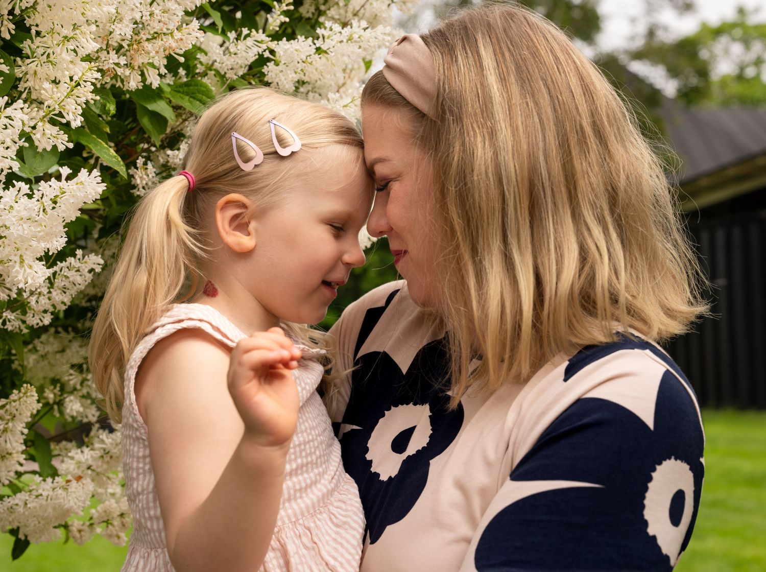 A tender moment shared between parent and child in spring, surrounded by blooming white flowers in a garden.