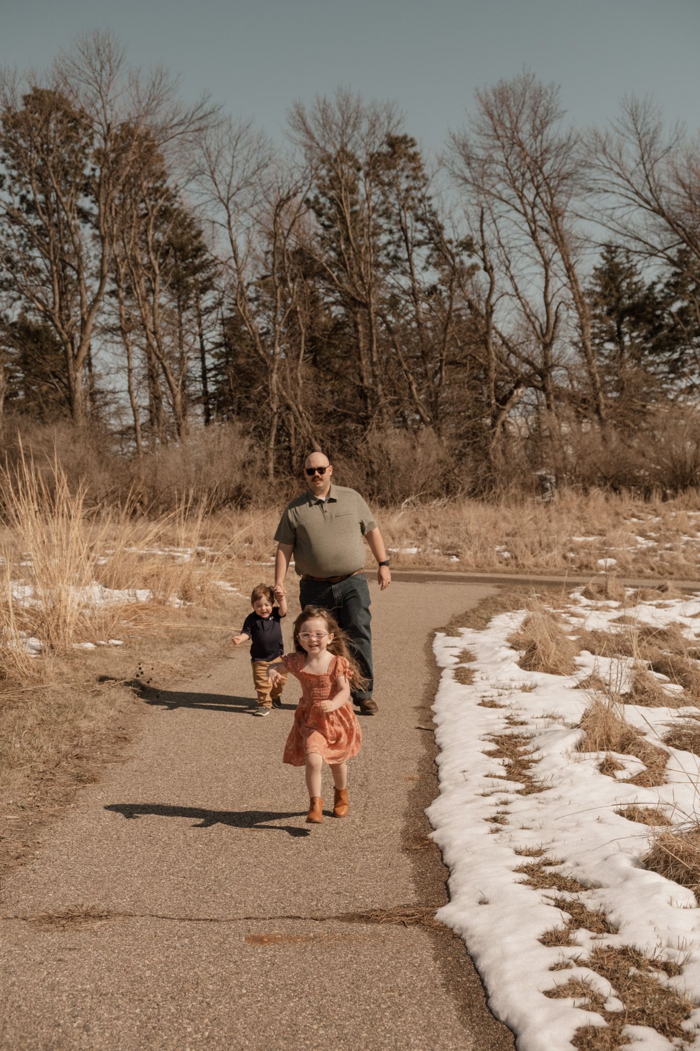 Winter walk along a snowy park trail during late afternoon with bare trees and seasonal scenery.