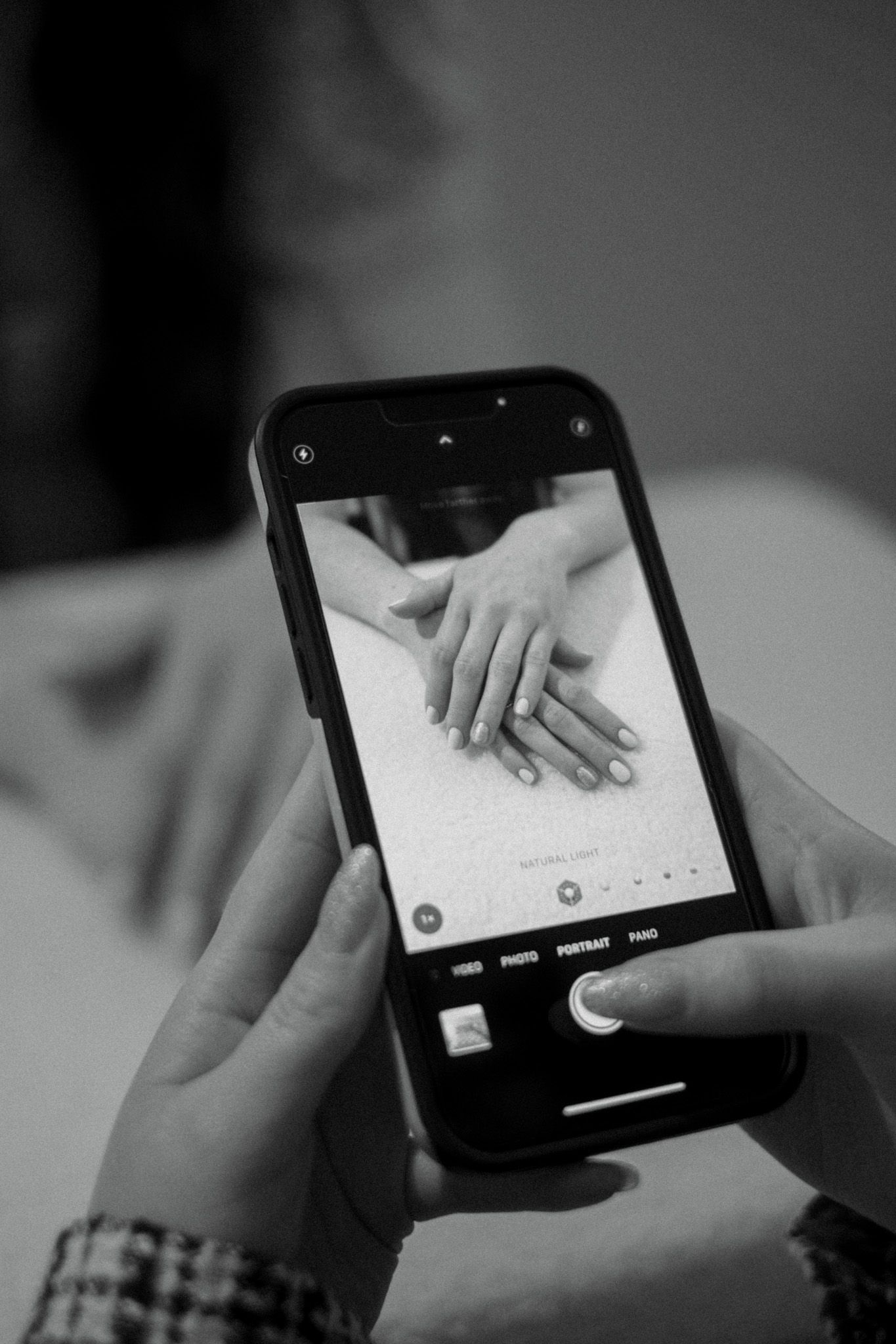 Hands interacting with a mobile device shown in a series of black and white shots capturing touch gestures.