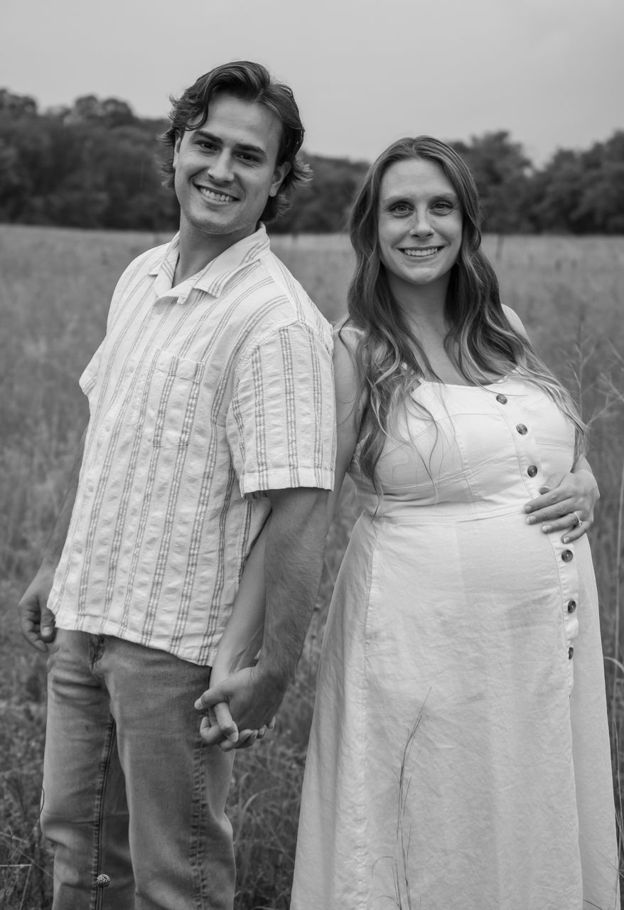 A couple poses together outdoors in black and white photos wearing casual attire during a countryside photoshoot.