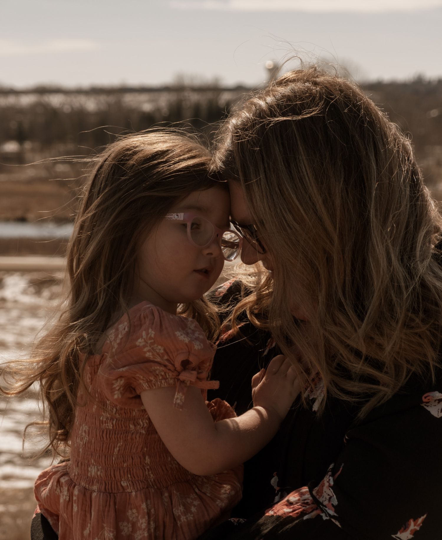 A tender moment captured in warm sepia tones between two figures outdoors on a sunny afternoon.