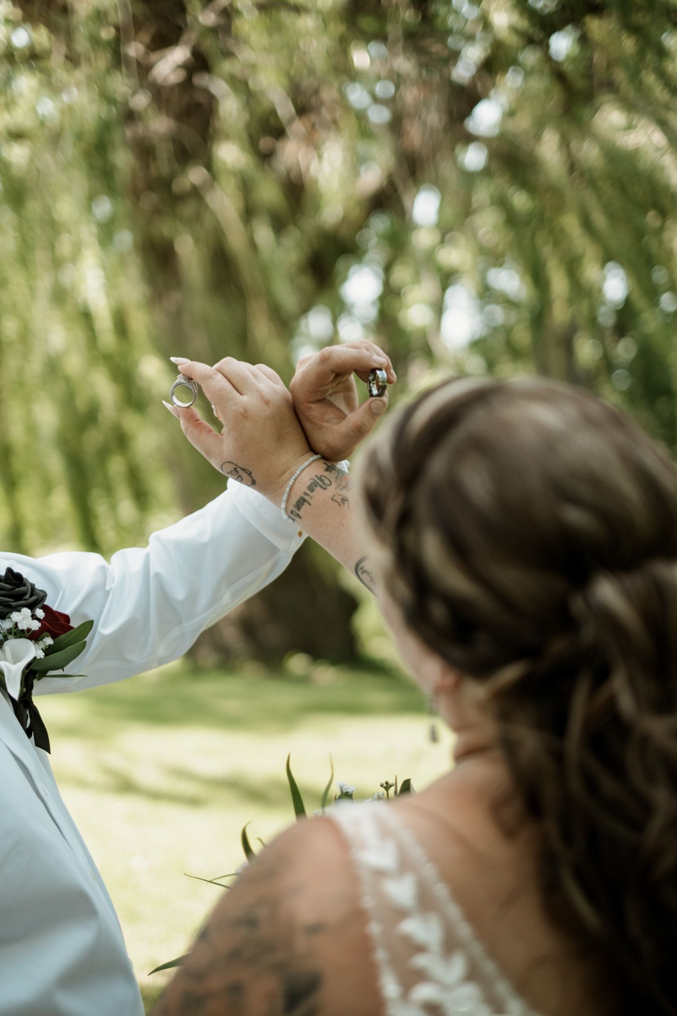 A heartfelt dance moment between two people outdoors with leafy green trees in the background.