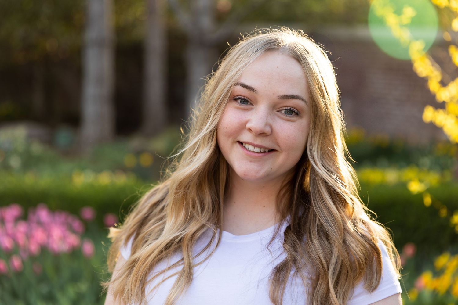 Kaylee Anne hair poses outdoors among colorful tulips and greenery.