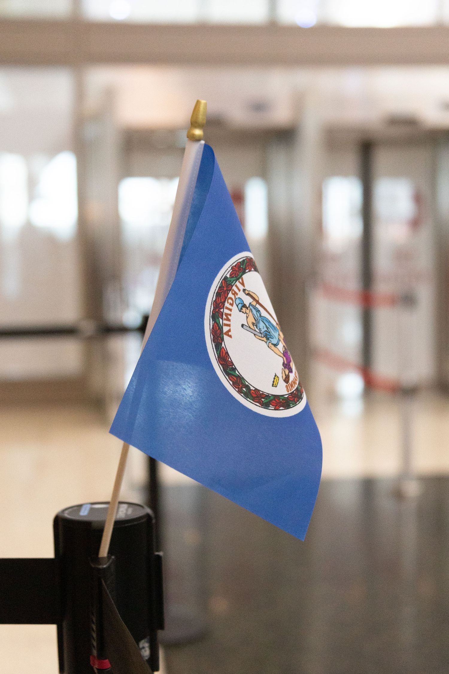 Small blue Virginia state flag on a stick displayed inside an airport terminal arrivals area in the Salt Lake airport.
