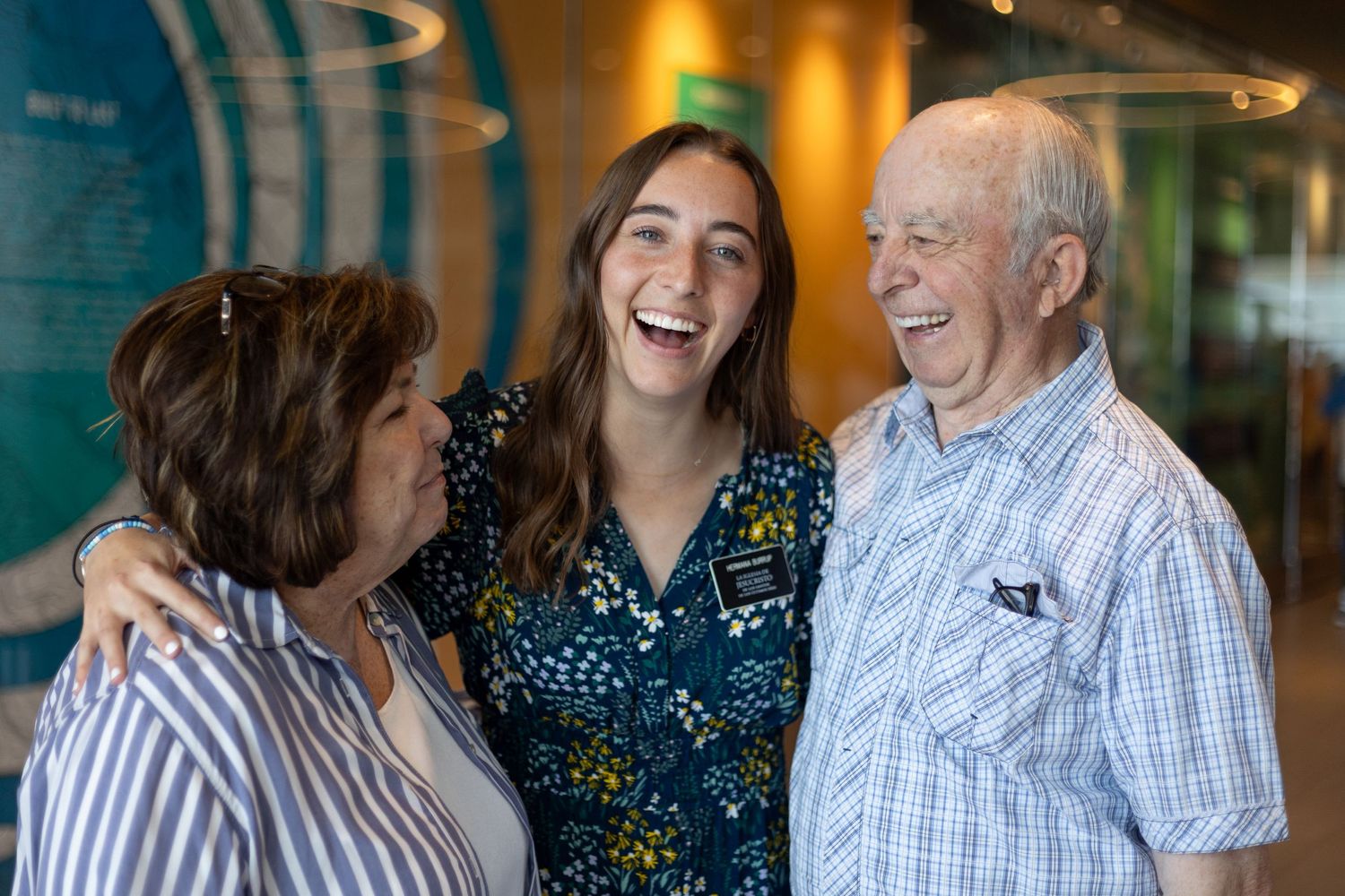Young LDS missionary woman laughing joyfully with her grandparents at homecoming.