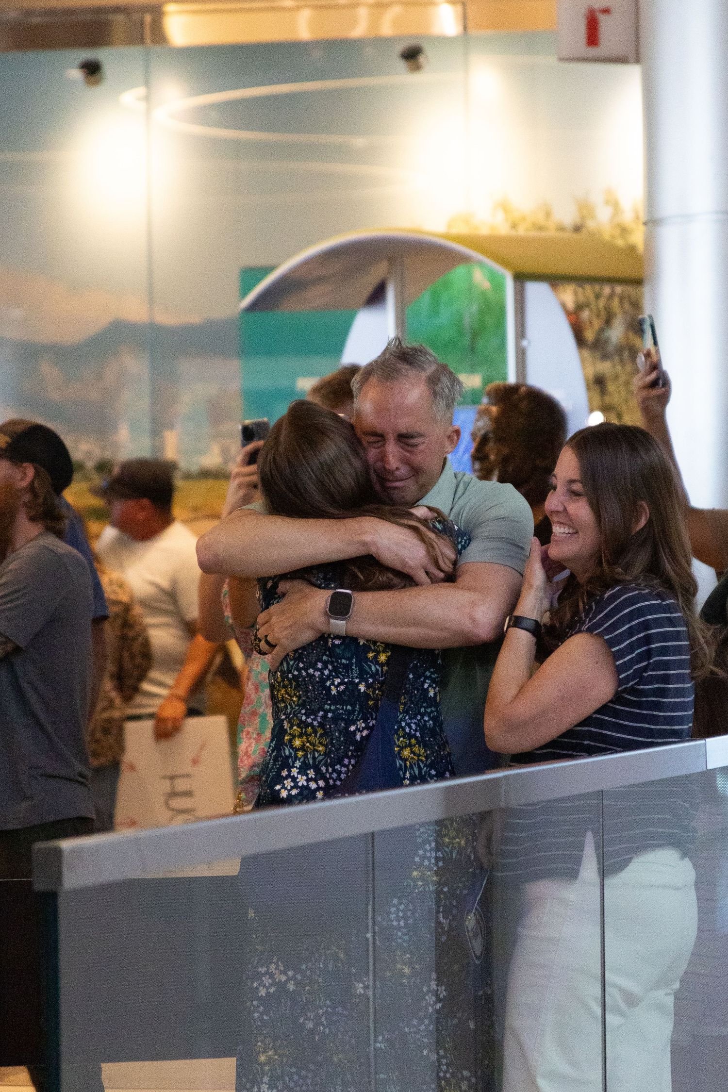 Dad hugs his returned missionary daughter during airport reunion.