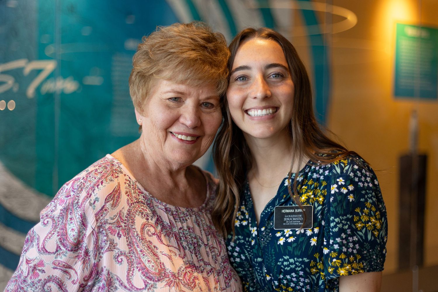 Returned missionary and her grandmother pose together indoors at a welcome home missionary celebration event.