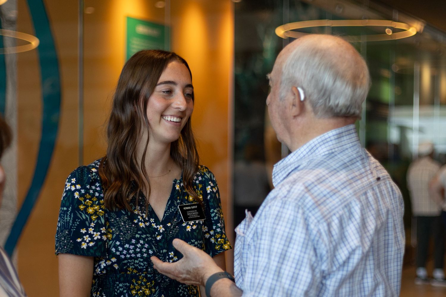 Young female LDS missionary smiling and conversing with her grandfather at the airport