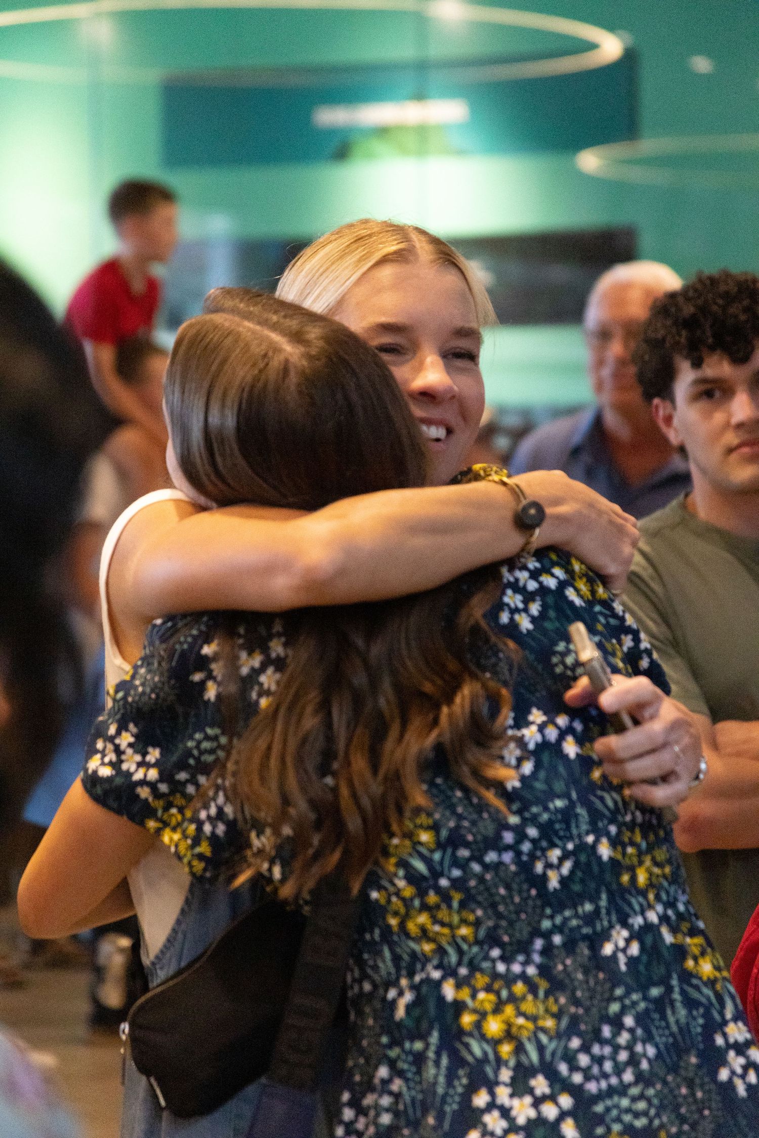 Friend and return missionary daughter share a joyful embrace at an airport reunion at the Salt Lake airport.