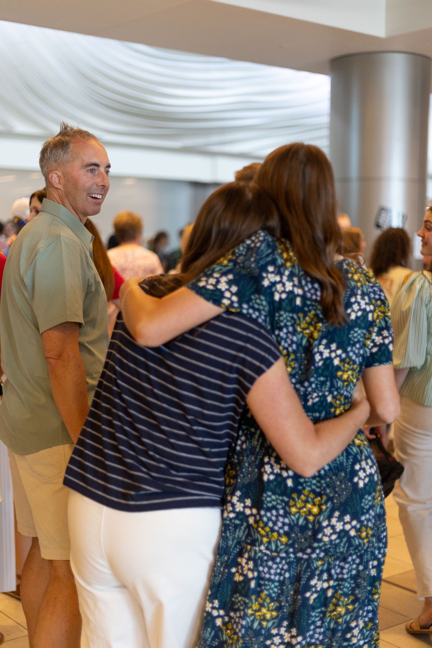 People greeting each other with hugs at a social gathering indoors.