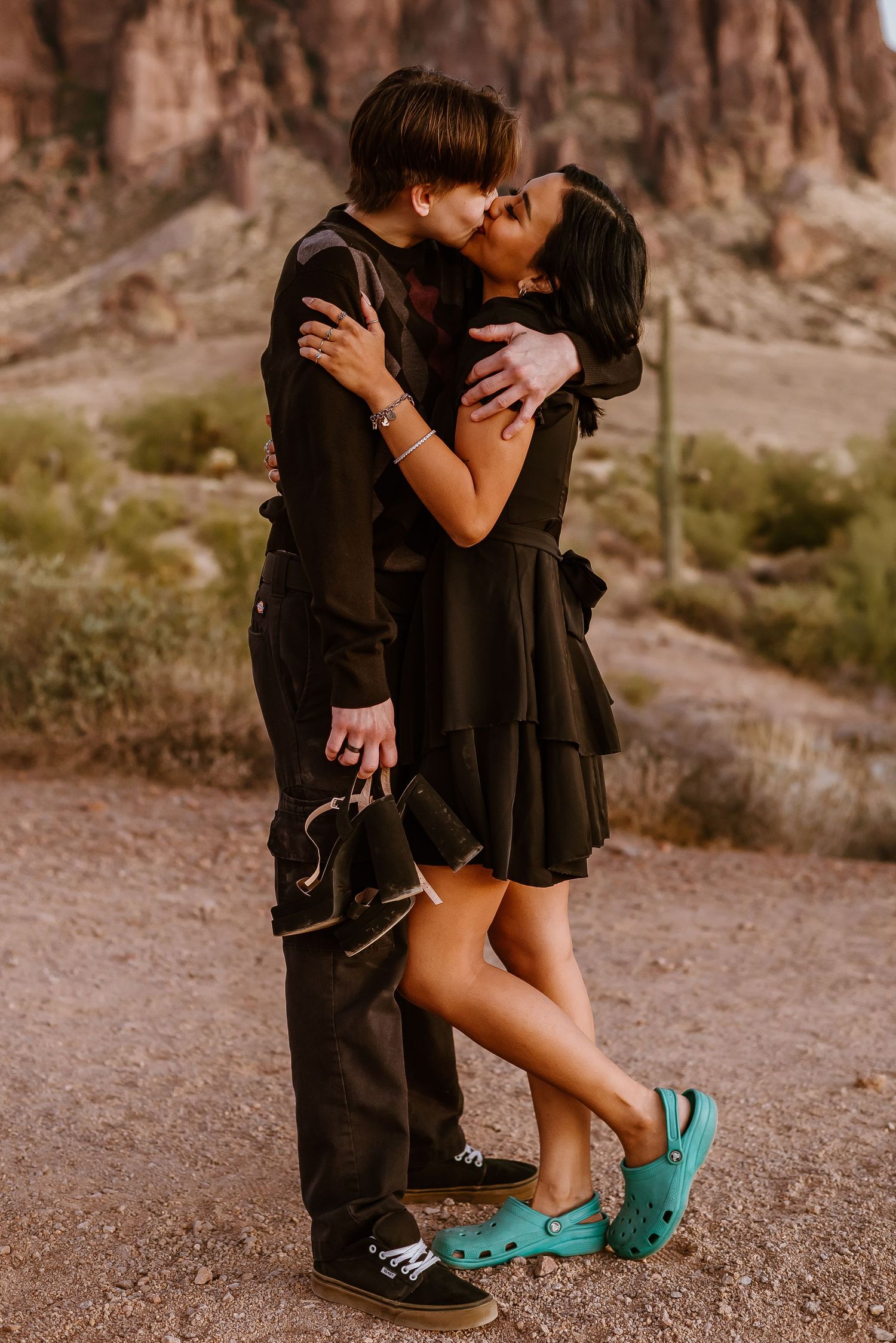 Intimate couple moment captured in front of desert scenery with one wearing turquoise shoes.