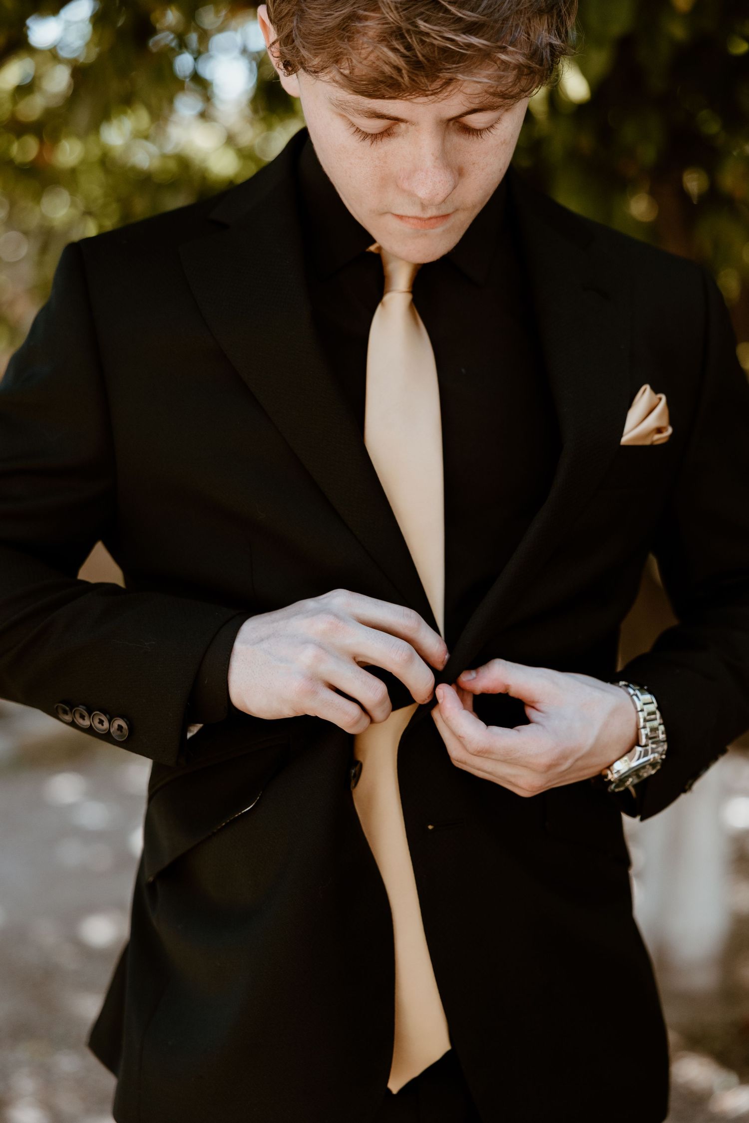 Detail shots of formal black suit adjustments during wedding preparation.