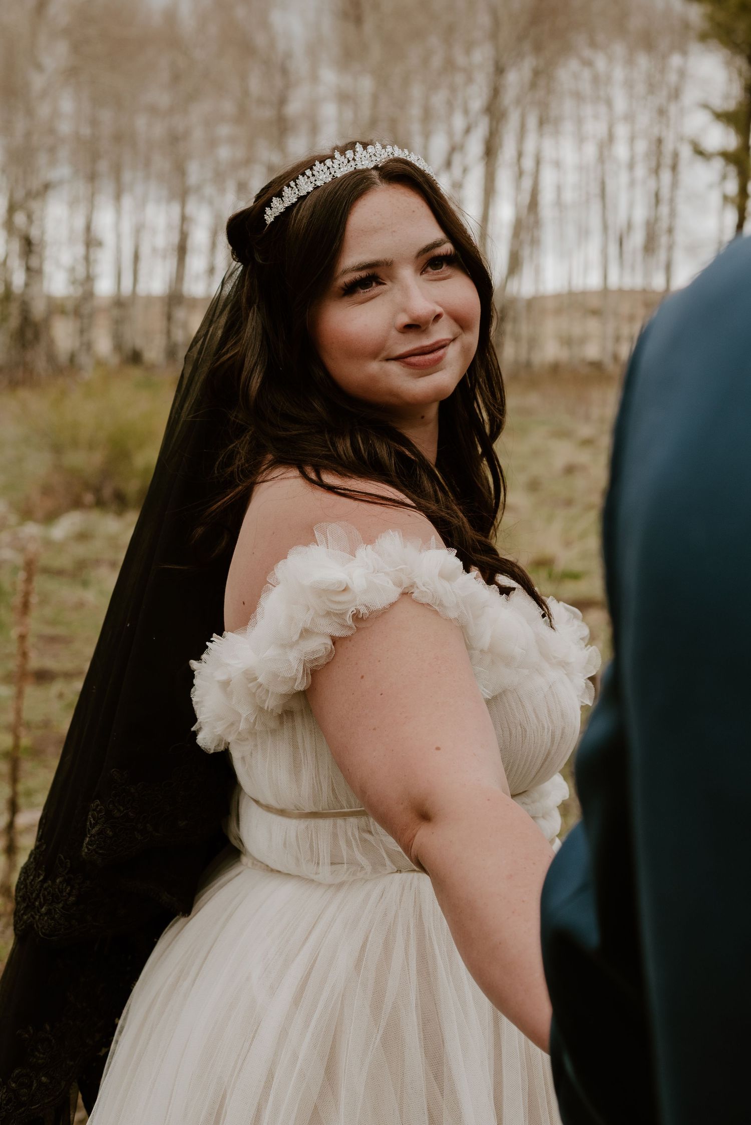 A wedding portrait showing an elegant white dress with ruffled details and a flowing black veil.