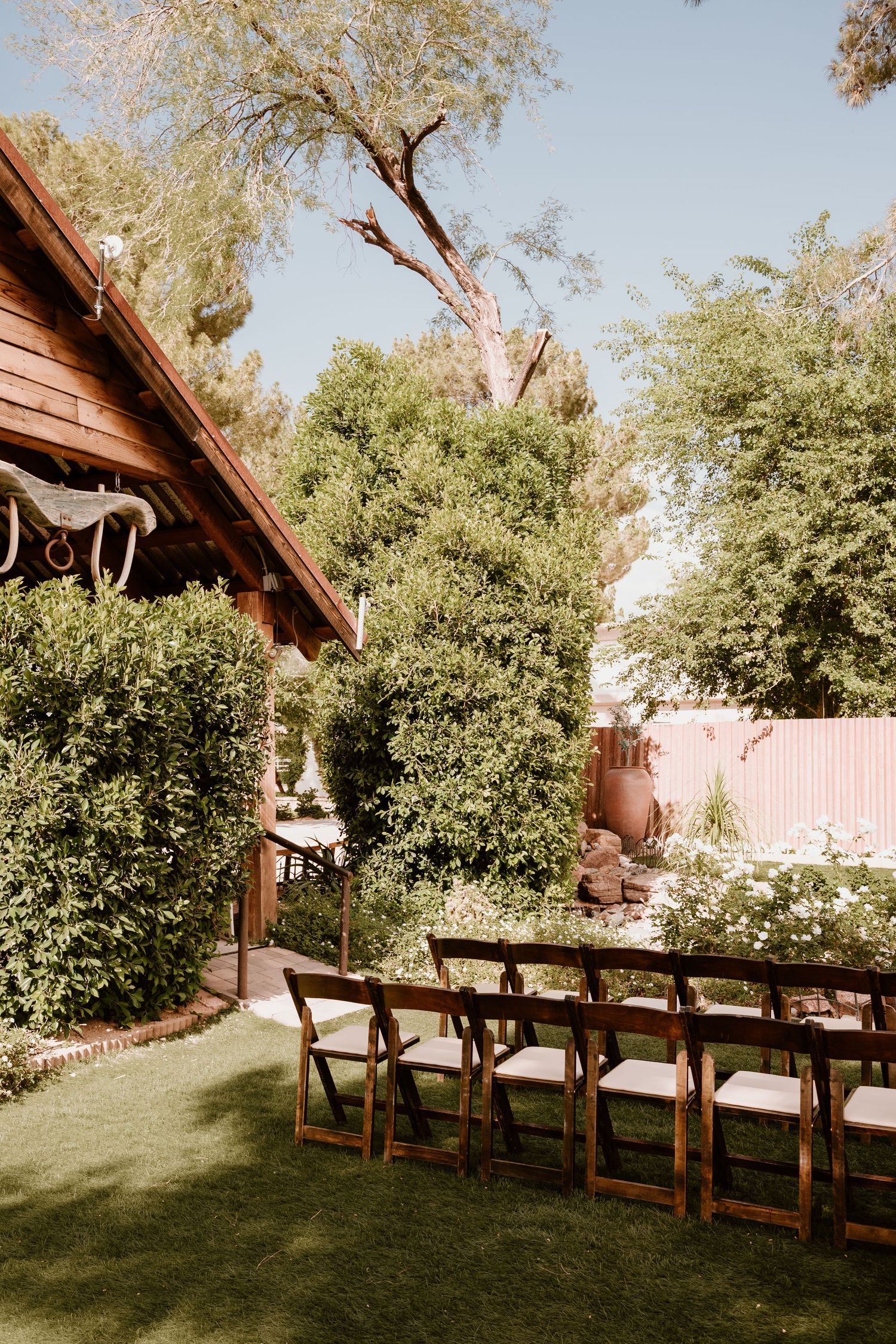 Wooden benches arranged in rows under shady trees for an outdoor ceremony or gathering.
