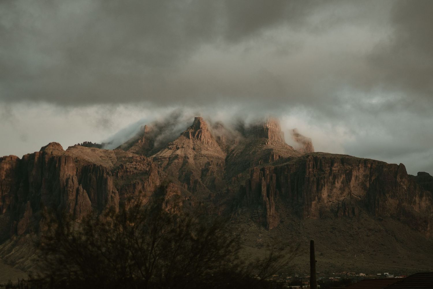 Dramatic mountain range under moody storm clouds at sunset.