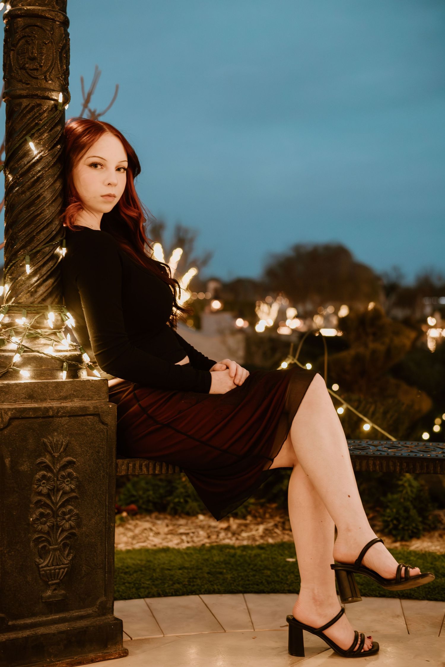Evening portrait with string lights decorating a pillar against a blue twilight sky.