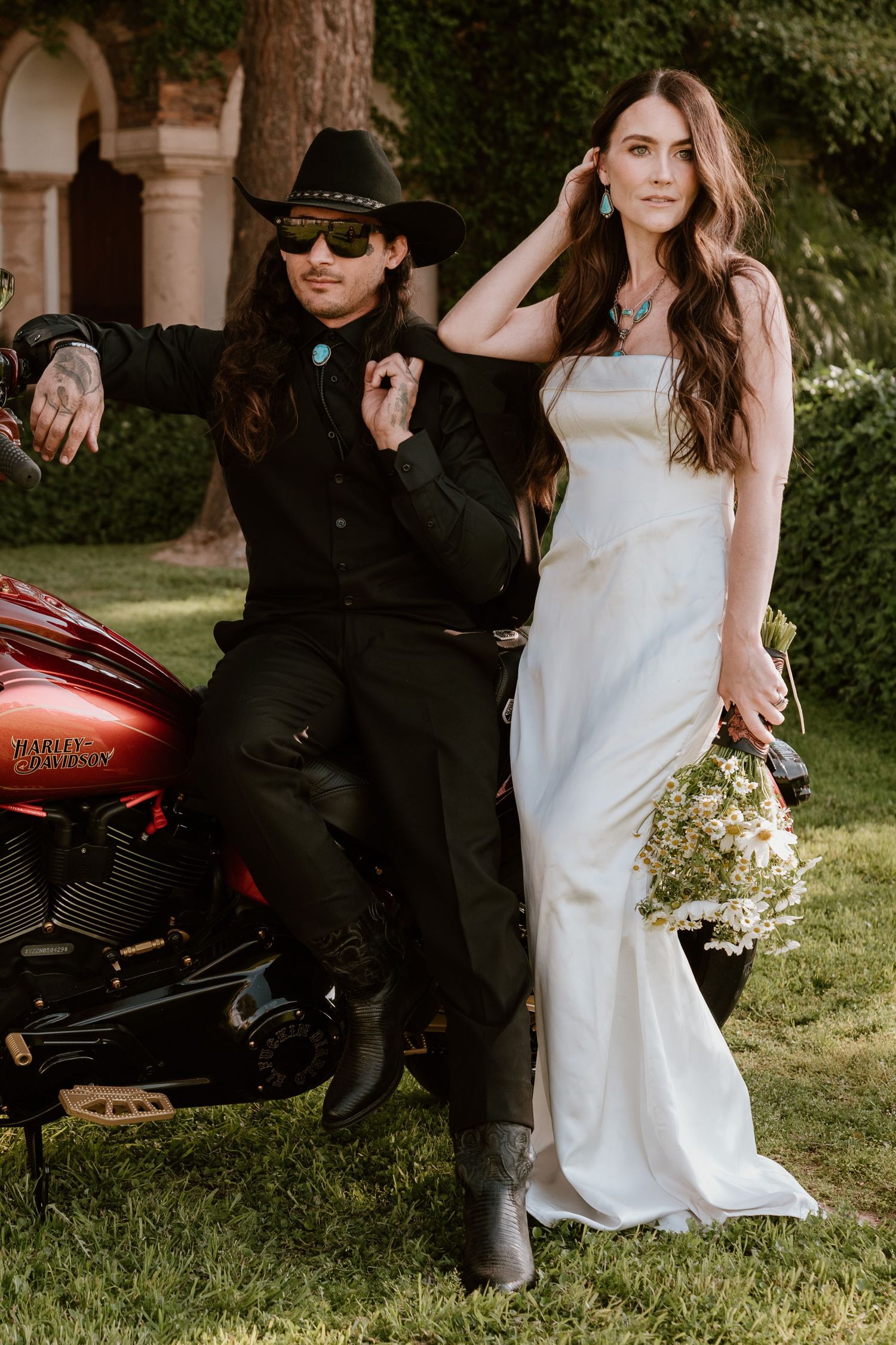 Wedding party poses outdoors with vintage motorcycle and contrasting black and white attire.