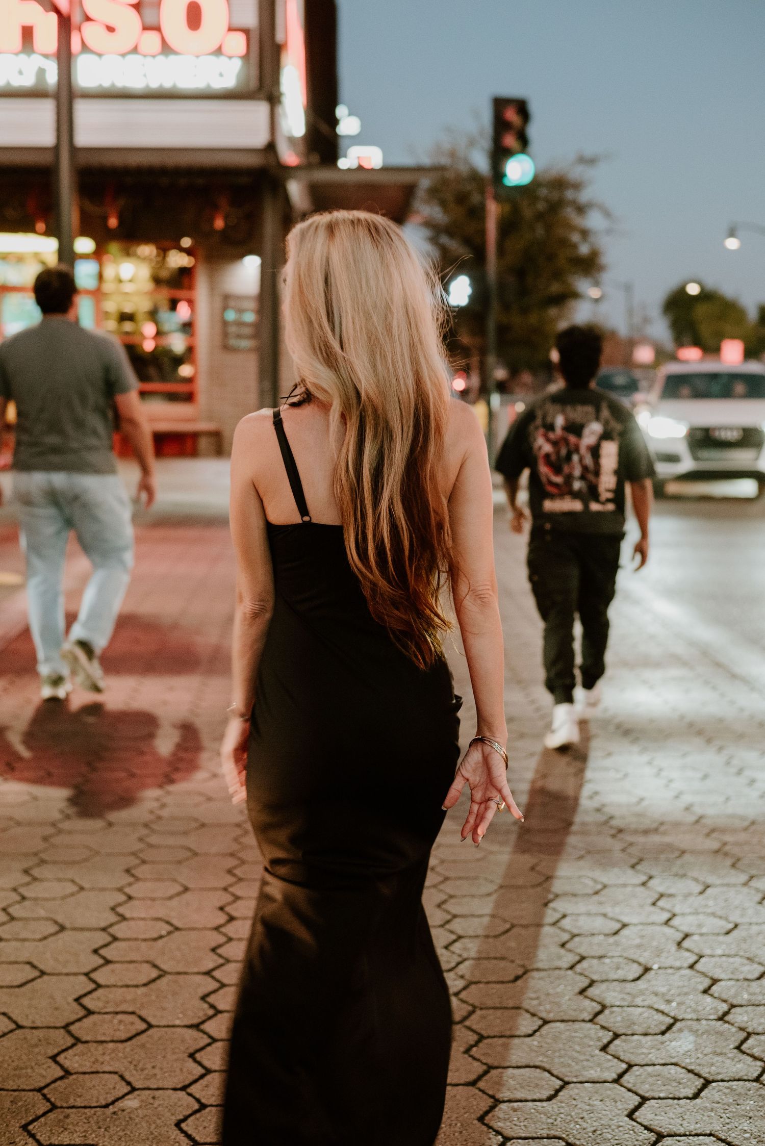 Silhouette walking on patterned sidewalk at dusk in urban setting.