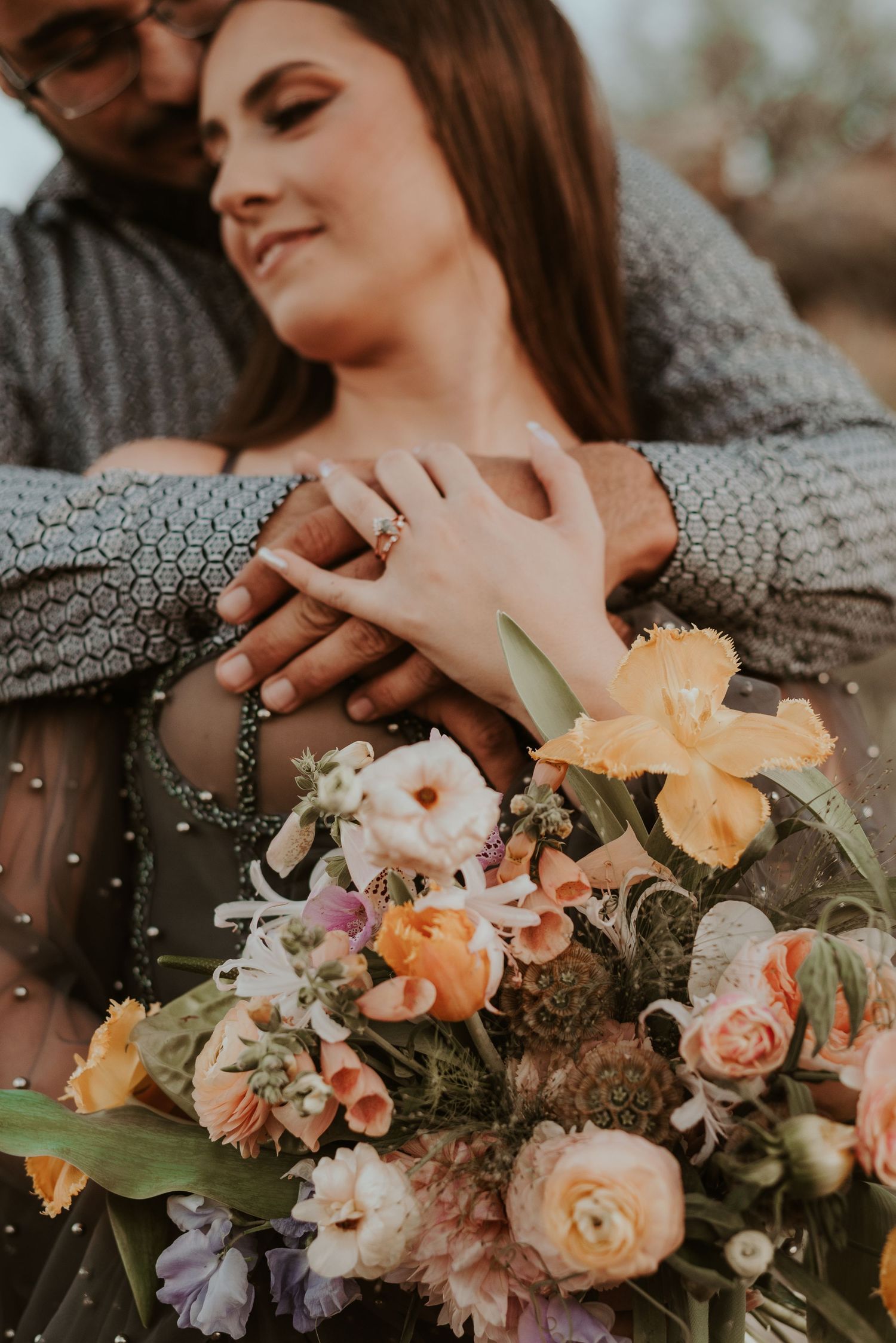 Couple sharing tender moment with peach and lavender floral arrangement.