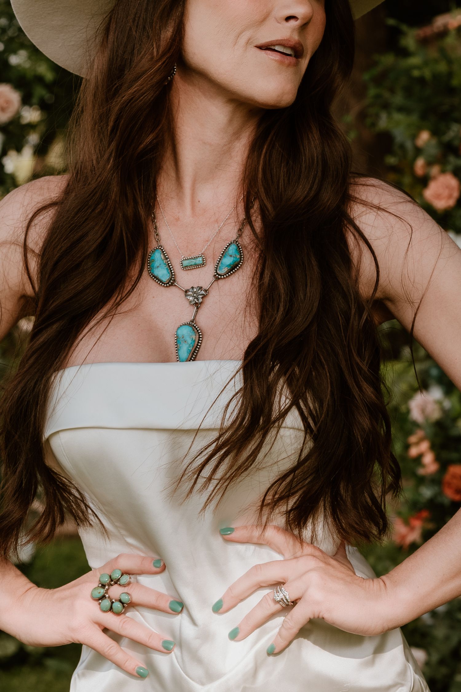 White dress detail with turquoise statement necklace and matching rings.