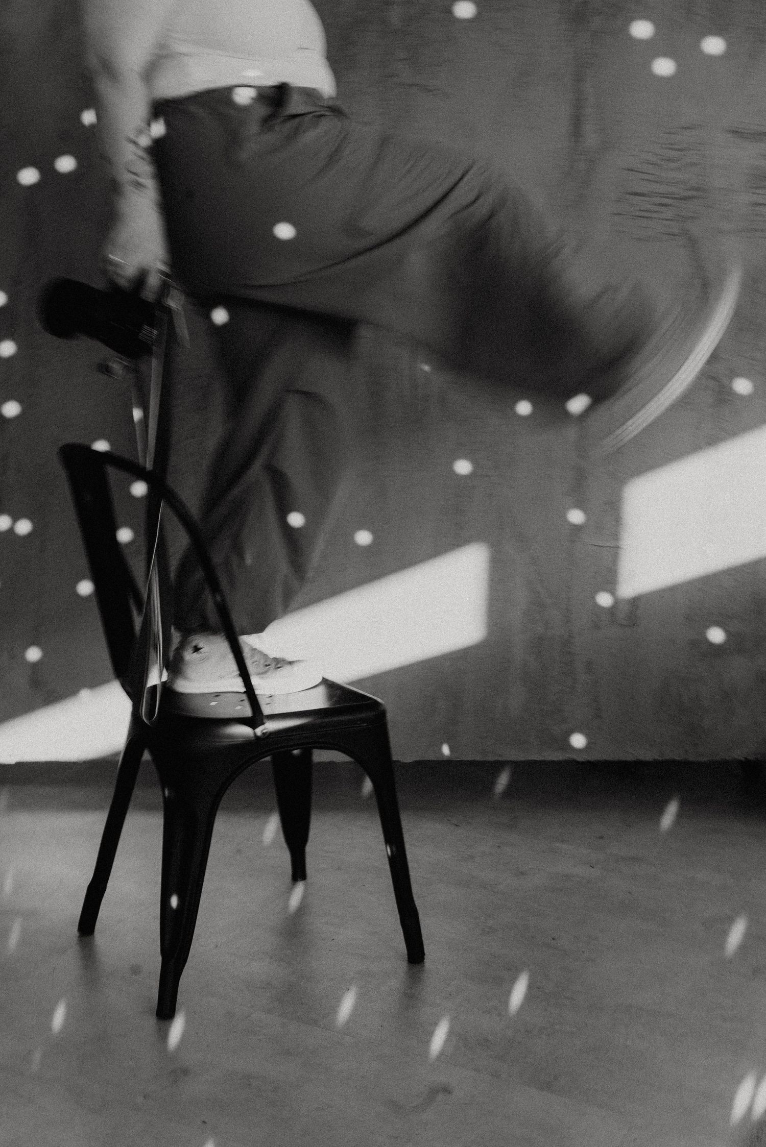 Black and white sequence showing movement against spotlit background with chairs.