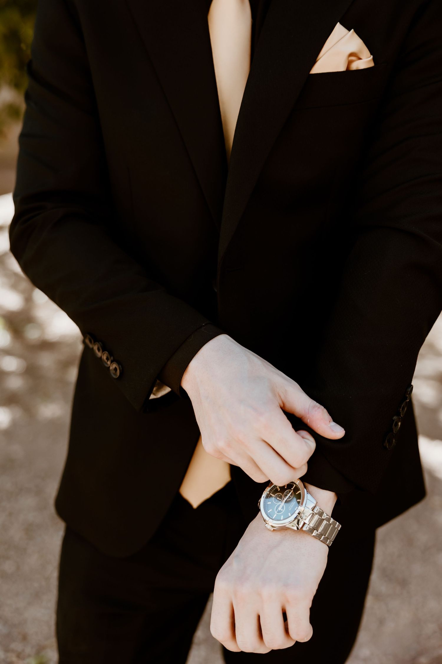 Close-up of hands wearing turquoise rings against black formal attire.