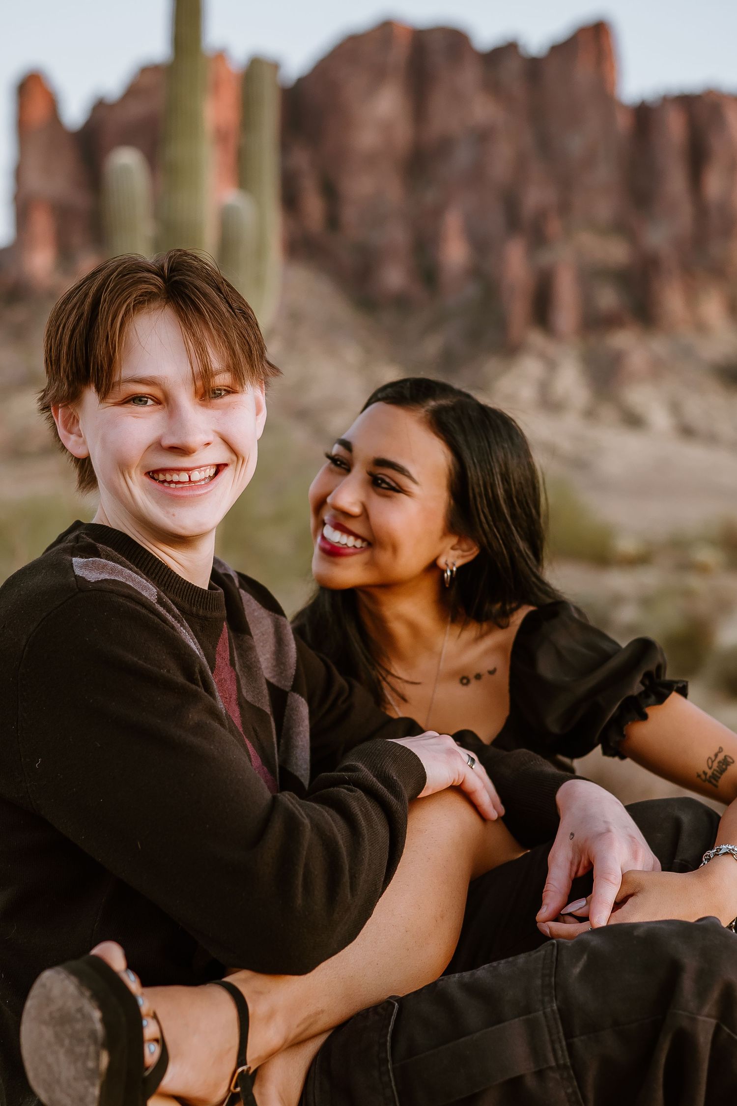 A romantic couple shares playful moments together against a desert landscape with rock formations.