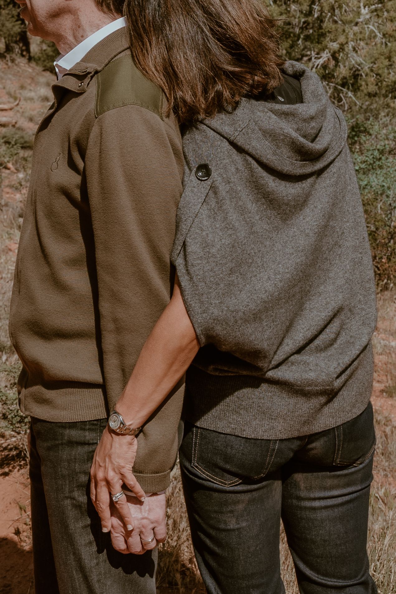 Close-up view of two people holding hands while walking together.