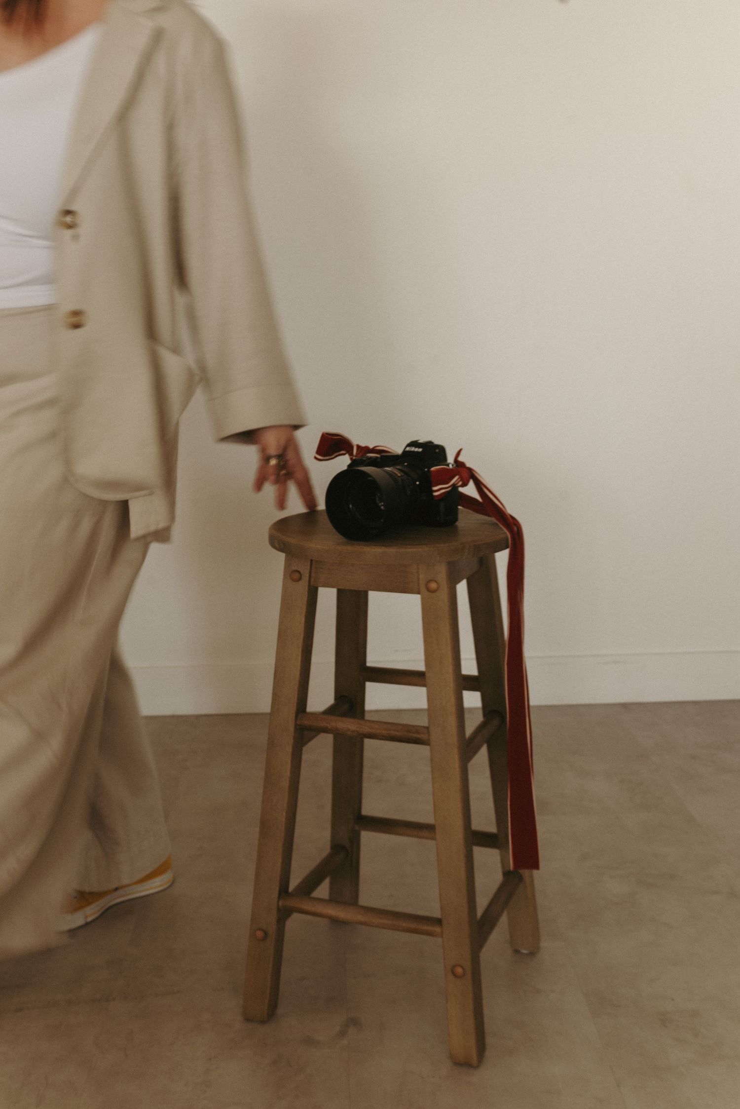 Wooden stool against white wall with personal items on top.