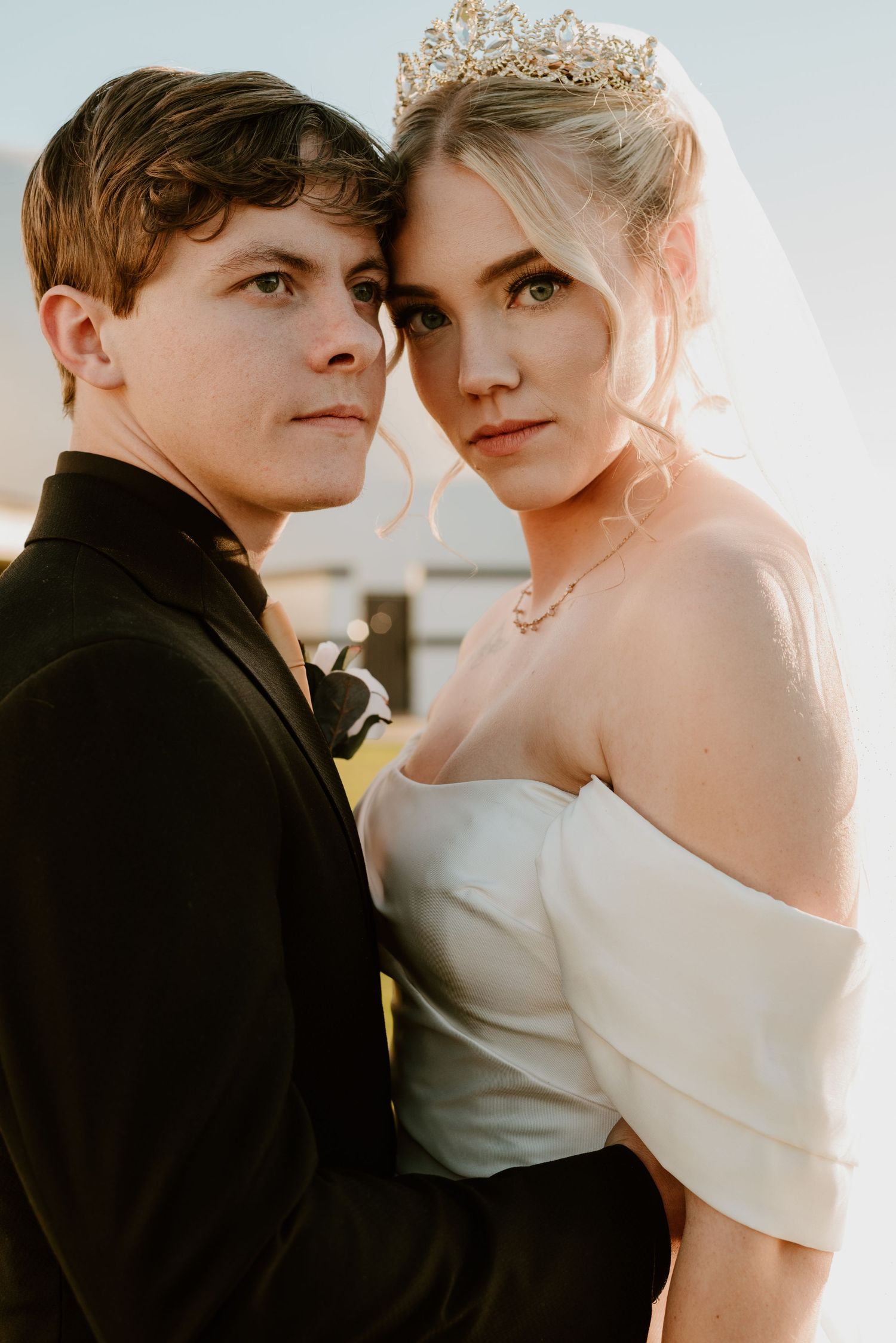 A romantic couple in formal attire poses for intimate wedding photos in soft lighting.