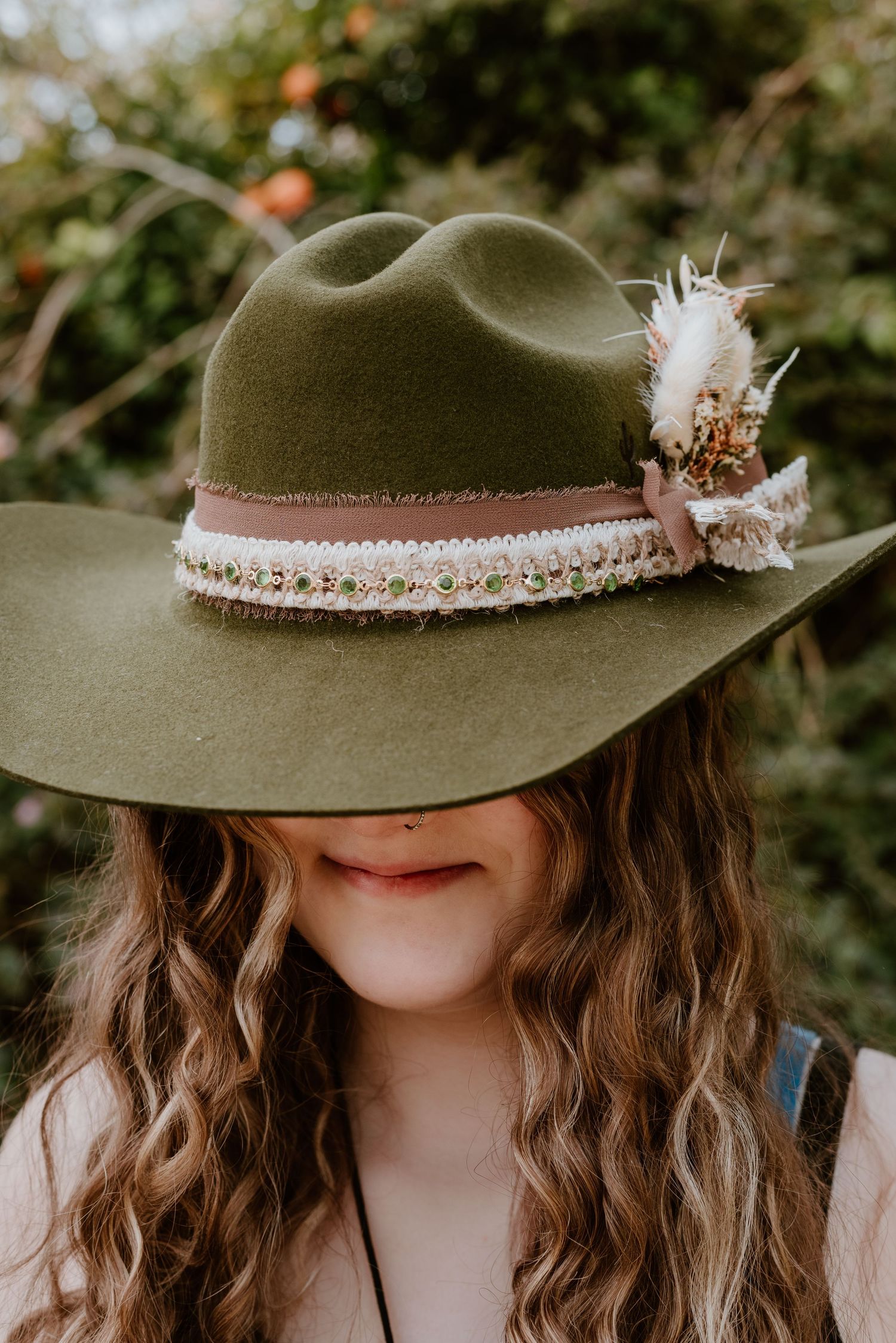 Green felt hat decorated with delicate lace trim and feather details.